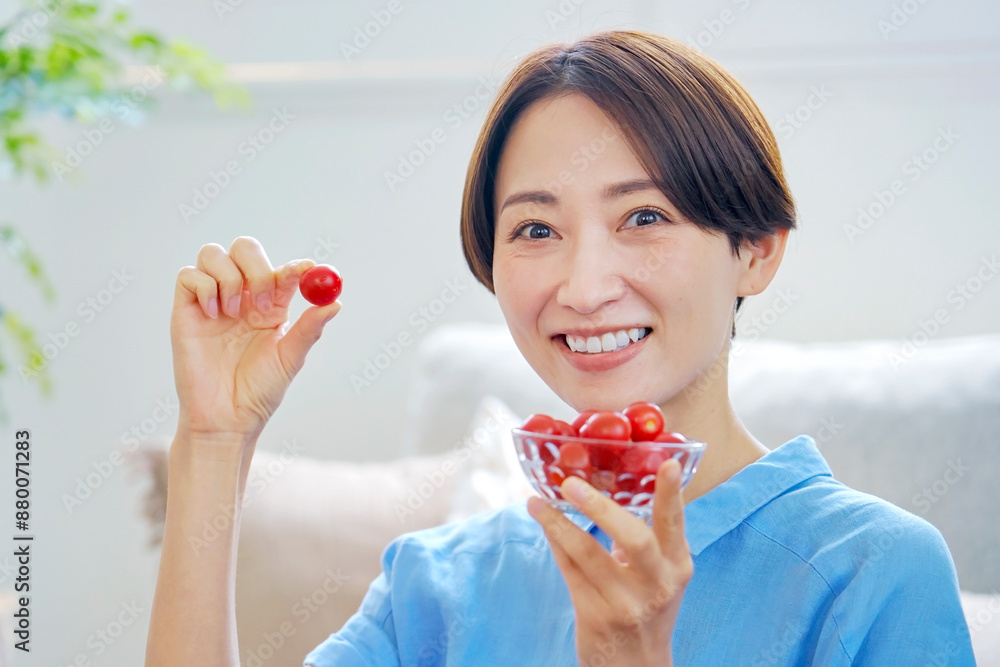 自宅でミニトマトを食べる女性　カメラ目線