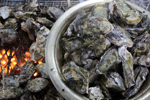Foto Close-up of raw oysters with shell being roasted on the grill and briquet fire w
