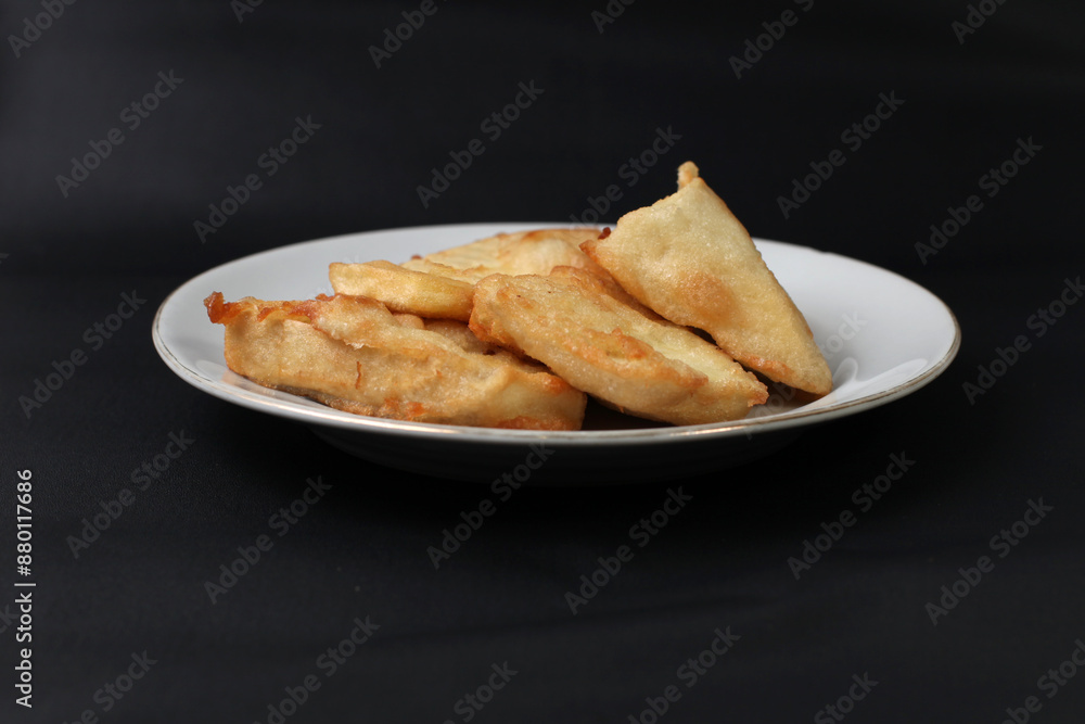 food made from thinly sliced breadfruit coated in a wheat flour mixture then fried until dry and crispy. Fried breadfruit isolated on black background. food made from thinly sliced breadfruit coated in a wheat flour mixture then fried until dry and crispy. Fried breadfruit isolated on black background.