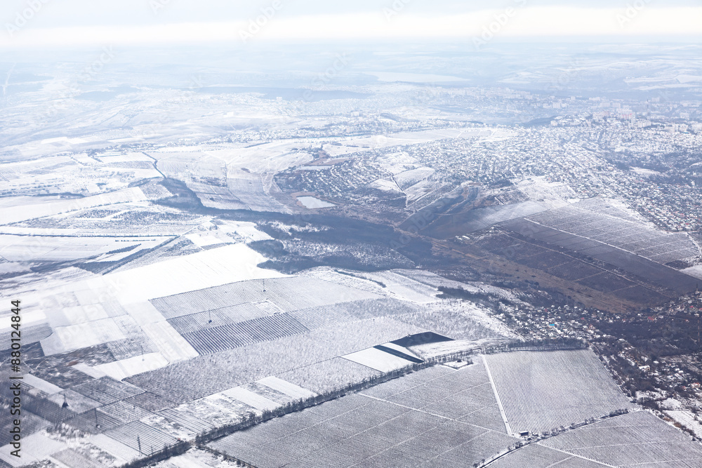 Winter scene with snow covering the ground and frosty trees. Sky is cloudy and the ground is covered in snow. Aerial view of winter countryside