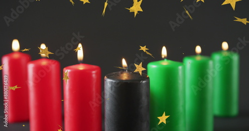 Image of golden stars over kwanzaa candles on black background