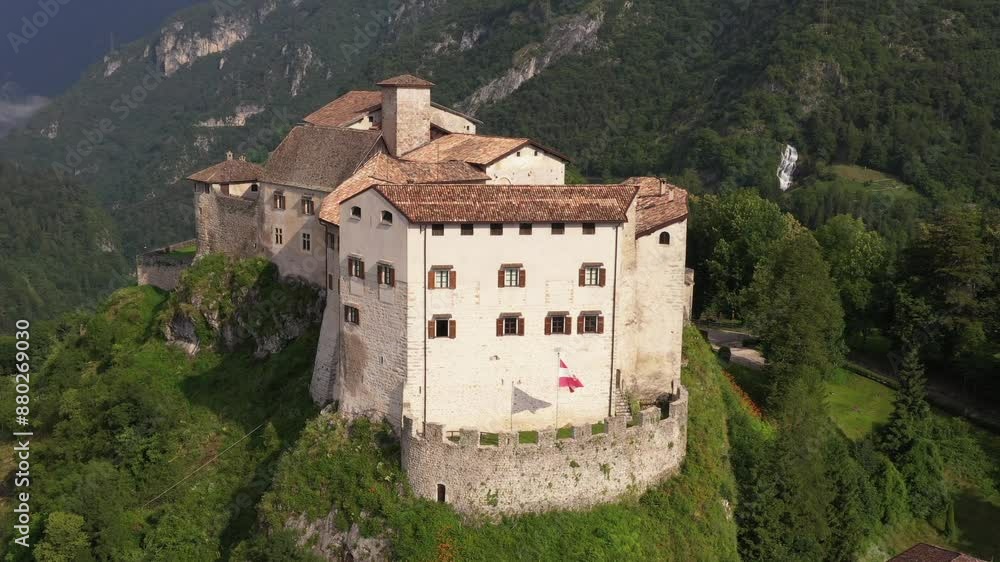 Slow flight up along the Castle of Stenico. Rio bianco natural area waterfall in the background. Summer view of Stenico Castle, highlighting its ancient architecture and historical significance. Slow flight up along the Castle of Stenico. Rio bianco natural area waterfall in the background. Summer view of Stenico Castle, highlighting its ancient architecture and historical significance.