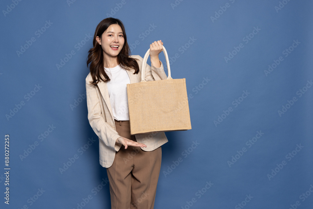 Happy Asian businesswoman holding textile eco bag or cloth bag isolated on blue background, Ecology or environment protection concept Happy Asian businesswoman holding textile eco bag or cloth bag isolated on blue background, Ecology or environment protection concept