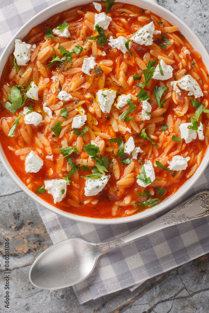 Mediterranean cuisine orzo pasta with spicy tomato sauce, feta, garlic, onion, carrots closeup on the plate on the table. Vertical top view from above Mediterranean cuisine orzo pasta with spicy tomato sauce, feta, garlic, onion, carrots closeup on the plate on the table. Vertical top view from above