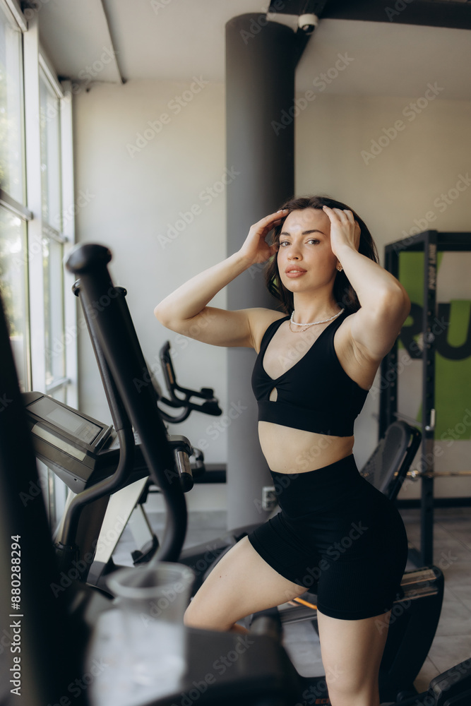 Attractive young woman is working out on an elliptical trainer in gym Attractive young woman is working out on an elliptical trainer in gym