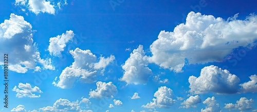 Fluffy clouds drift peacefully in a clear blue sky, offering a serene copy space image. photo