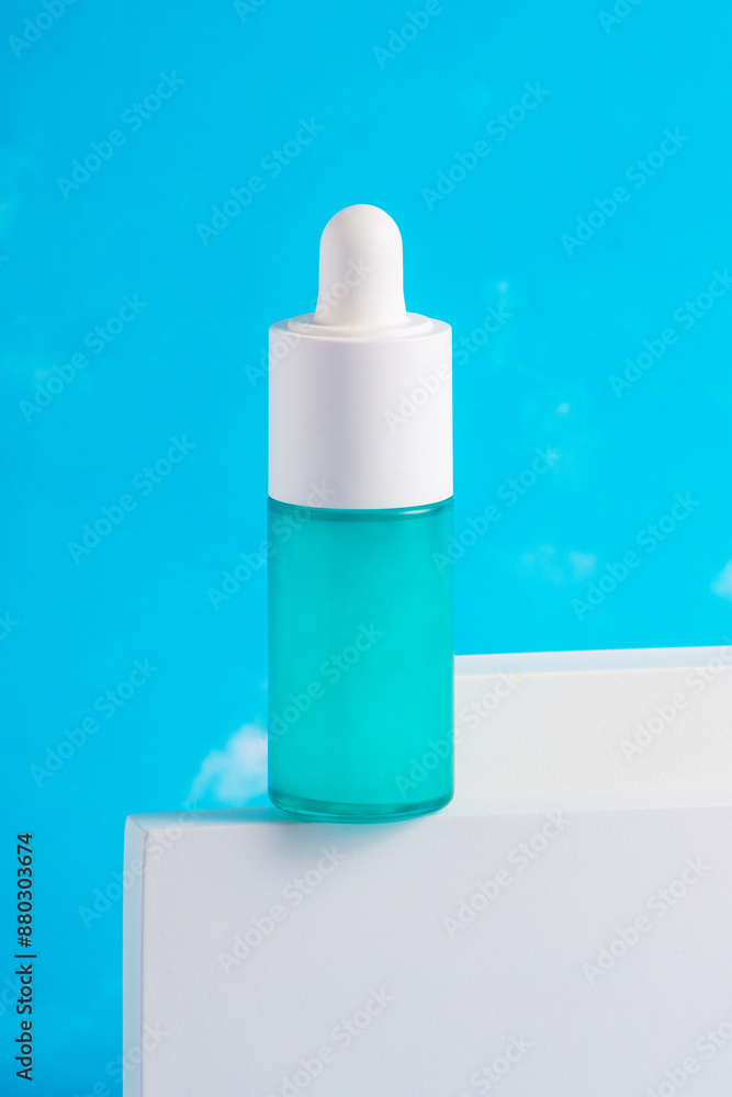 Blue glass cosmetic bottle, Skin care or sunscreen cosmetic with stylish props on sky background. Blue glass cosmetic bottle, Skin care or sunscreen cosmetic with stylish props on sky background.