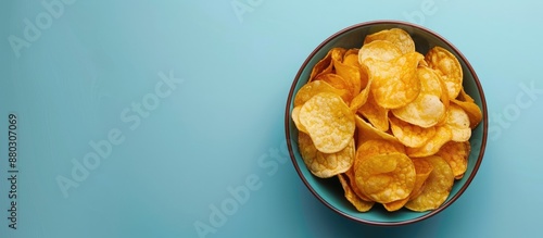 Top view of crispy potato chips in a bowl on a blue background with ample copy space image. photo