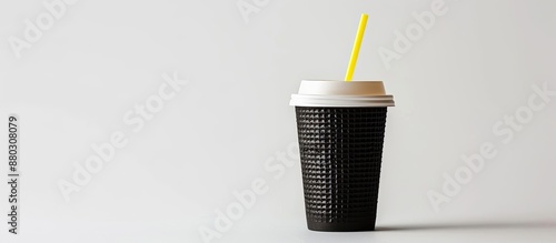 Disposable black paper coffee cup with a yellow plastic straw is displayed on a white background for a coffee to go concept, ideal for restaurants and cafes, featuring copy space image. photo