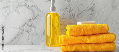 Clean cotton towels stacked next to a clear bottle of yellow shampoo, body gel, and hand soap, with room for additional text or images in the picture. photo