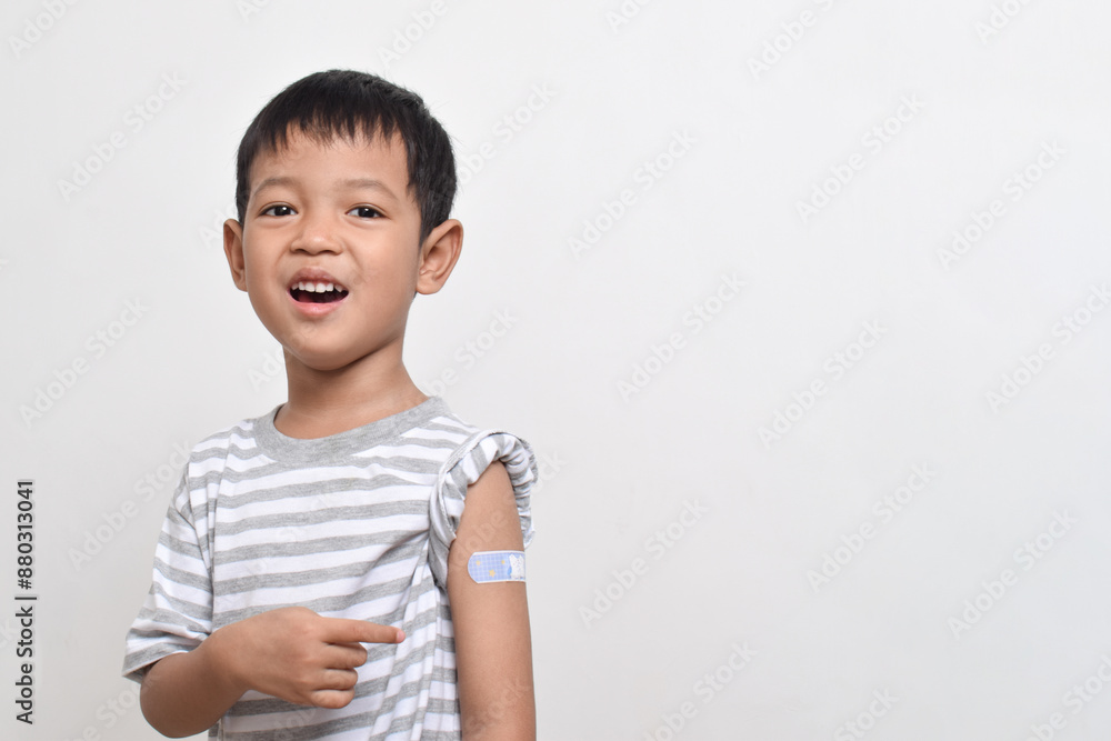 Asian boy shows his arm with bandage after virus vaccine. Child vaccination. Protect your child with vaccine concept. copy space Asian boy shows his arm with bandage after virus vaccine. Child vaccination. Protect your child with vaccine concept. copy space