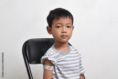 Asian boy with plaster bandage on his arm after vaccination. Vaccine injection. Health services for children. copy space