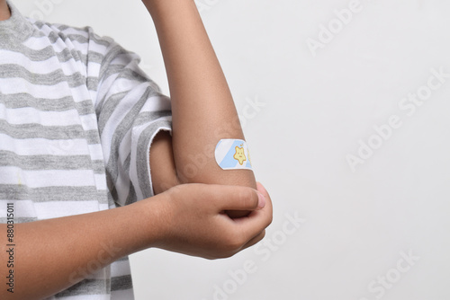 Asian child's elbow with adhesive bandage and wound on arm. Plaster bandage on the child's elbow photo