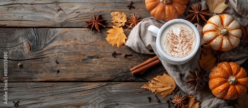 Fototapeta Naklejka Na Ścianę i Meble -  Autumn vibes with a pumpkin spiced latte in a white cup on a rustic wooden backdrop featuring pumpkins cinnamon and spices perfect for a copy space image