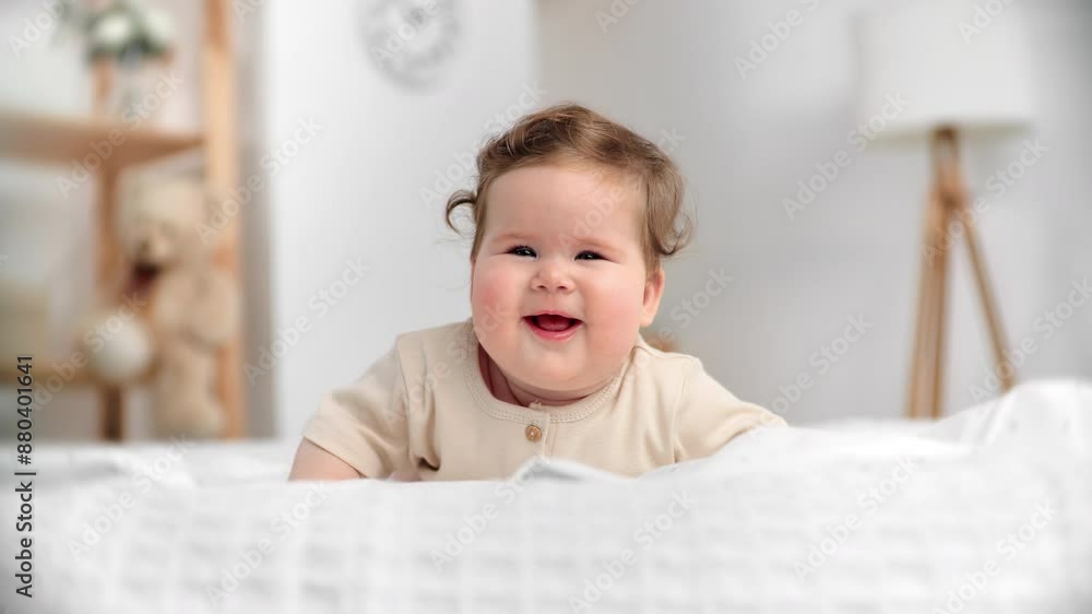 Cute baby girl smiling and laughing lying on bed in bedroom, happy childhood moments, portrait Cute baby girl smiling and laughing lying on bed in bedroom, happy childhood moments, portrait