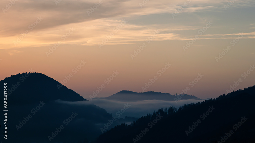 Fototapeta premium Sunset above horizon line with sun setting down behind mountains