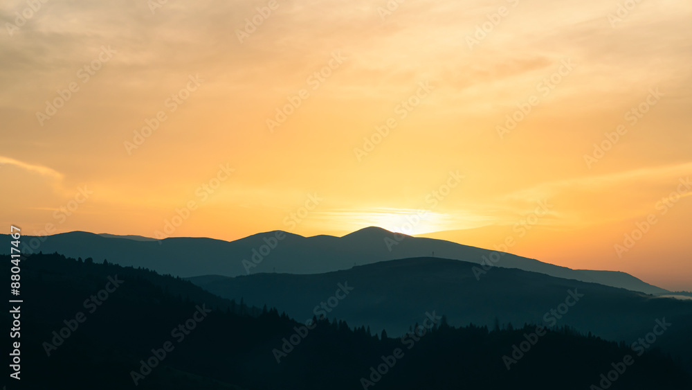 Sunset above horizon line with sun setting down behind mountains Sunset above horizon line with sun setting down behind mountains