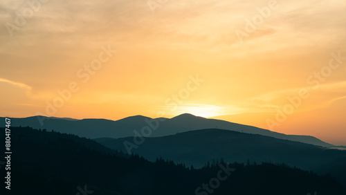 Sunset above horizon line with sun setting down behind mountains