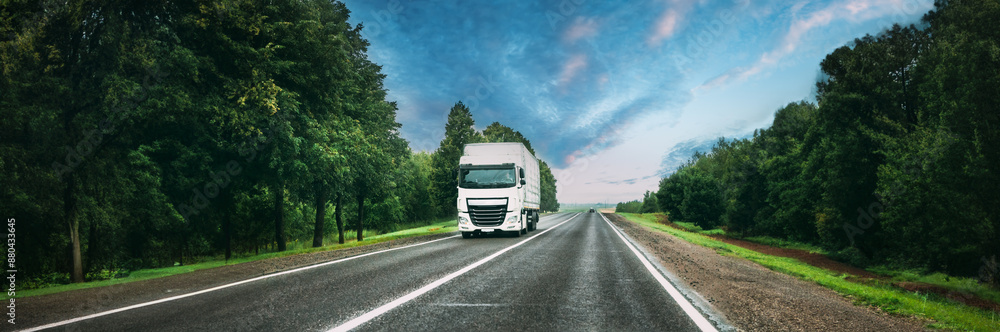 Truck Tractor Unit, Prime Mover, Traction Unit In Motion On Road, Freeway. Asphalt Motorway Highway Against Background Of Forest Landscape. Business Transportation And Trucking Industry Truck Tractor Unit, Prime Mover, Traction Unit In Motion On Road, Freeway. Asphalt Motorway Highway Against Background Of Forest Landscape. Business Transportation And Trucking Industry