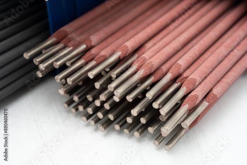 Red welding rods and electrodes on a white background. Close-up of welding electrodes in industrial setting - Metal rods with protective coating. High-Quality electrodes for professional welding.