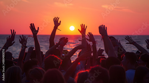 A group of teenagers stands, arms raised and waving joyfully towards the setting evening sun, capturing a moment of youthful exuberance and freedom against a backdrop of vibrant colors.