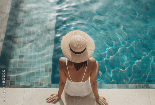 woman wearing straw hat and white swimming suit sitting on the edge of pool