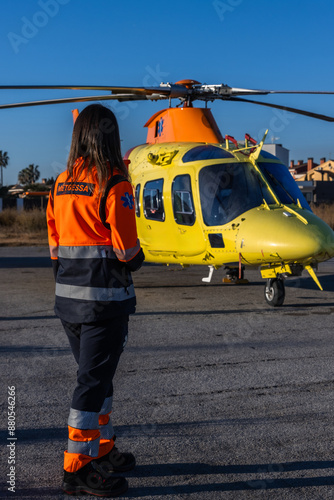 Foto Paramedic looking at the medical helicopter that is landed at the airfield