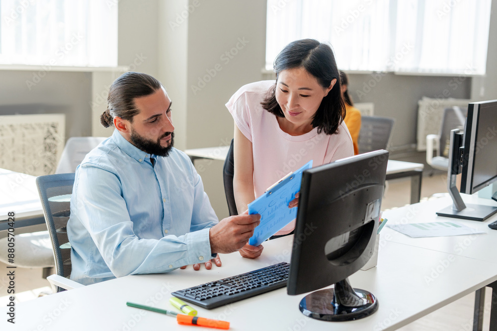 Attractive middle aged Arab ceo businessman holding documents, his beautiful Asian secretary talking Attractive middle aged Arab ceo businessman holding documents, his beautiful Asian secretary talking