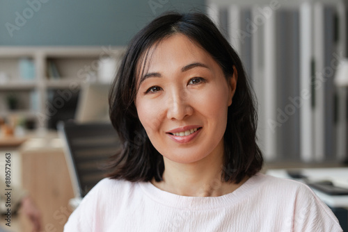 Photography Portrait of smiling, attractive Asian woman smiling posing in office looking at