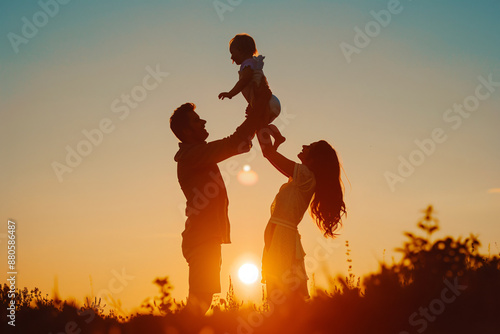 Silhouette of happy family with child playing at sunset, mother and father holding their baby up in the air on beautiful summer day, realistic photo shoot