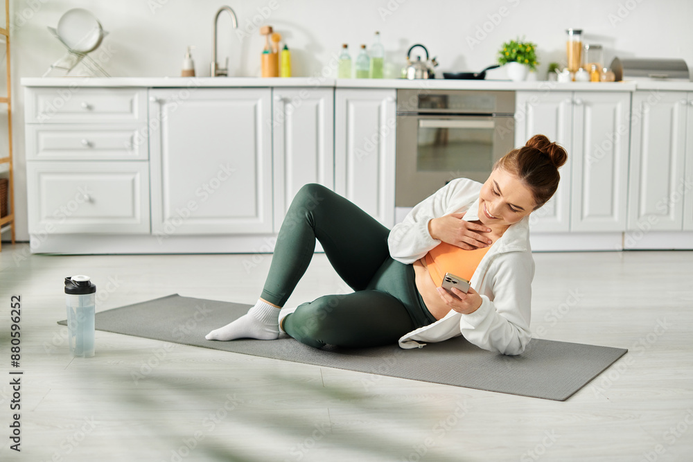 Middle-aged woman sitting on yoga mat, holding cell phone. Middle-aged woman sitting on yoga mat, holding cell phone.