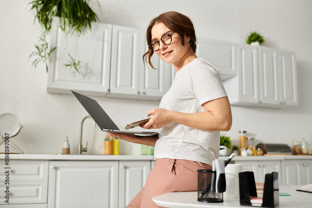 Middle aged woman sitting on counter, using laptop. Middle aged woman sitting on counter, using laptop.