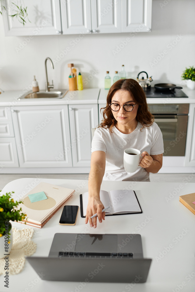 Middle aged woman working on a laptop at a kitchen table. Middle aged woman working on a laptop at a kitchen table.