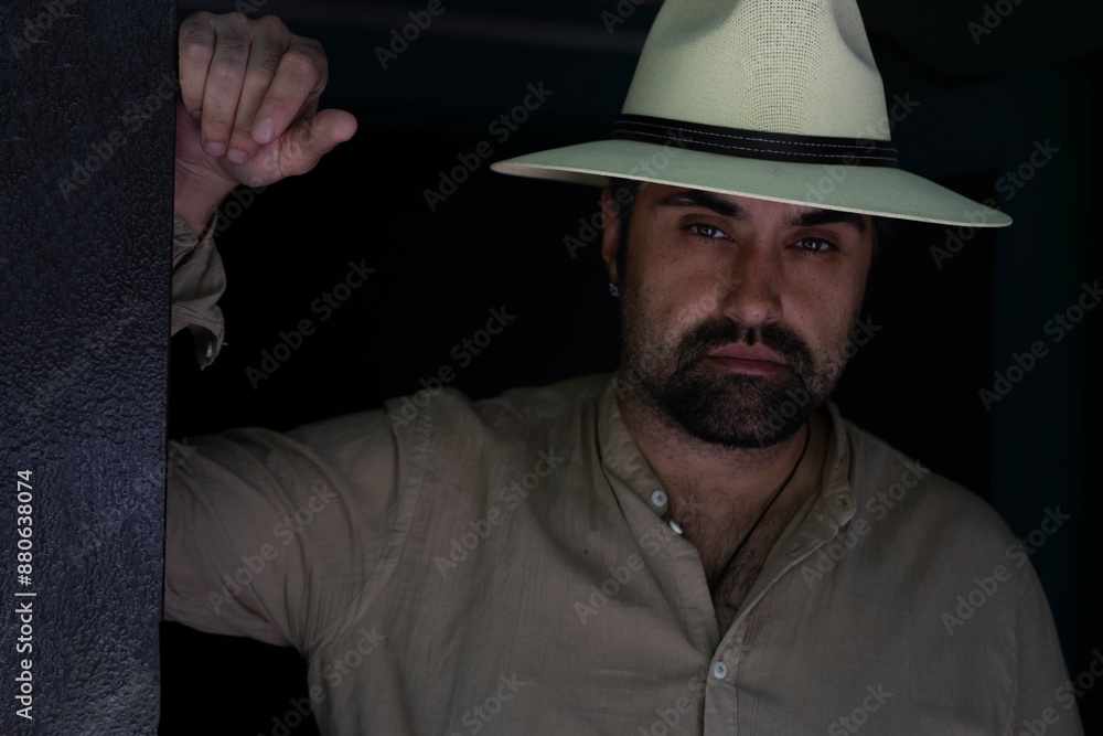 Portrait of a handsome bearded man in a shirt and white hat. A tired man with an expressive gaze looks at the camera, leaning his hand on the door frame. High quality photo Portrait of a handsome bearded man in a shirt and white hat. A tired man with an expressive gaze looks at the camera, leaning his hand on the door frame. High quality photo
