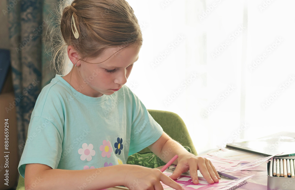 Girl drawing paper dolls in living room at table. Children and hobby during school vacation. Girl drawing paper dolls in living room at table. Children and hobby during school vacation.