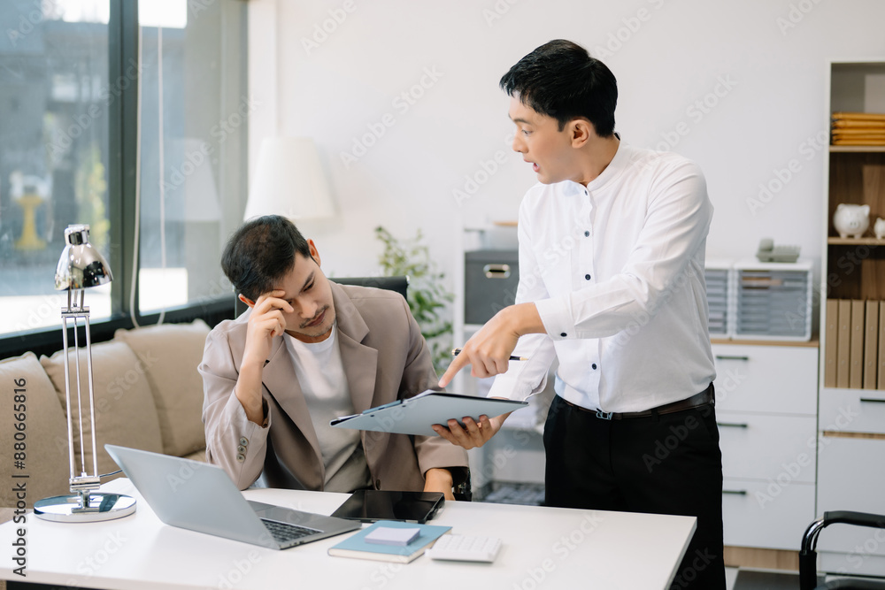 Furious two Asian businesspeople arguing strongly after making a mistake at work Furious two Asian businesspeople arguing strongly after making a mistake at work