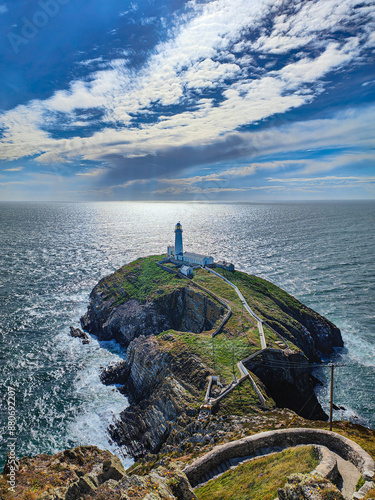 A spectacular steep path with steps leading to the South Stack Lighthouse on the cliff. Rocky island, rugged coastline, Irish Sea and blue sky. Holyhead, Anglesey, Wales photo