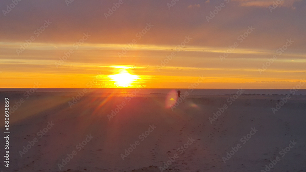 Fototapeta premium One person alone walking on a beach at sunrise.