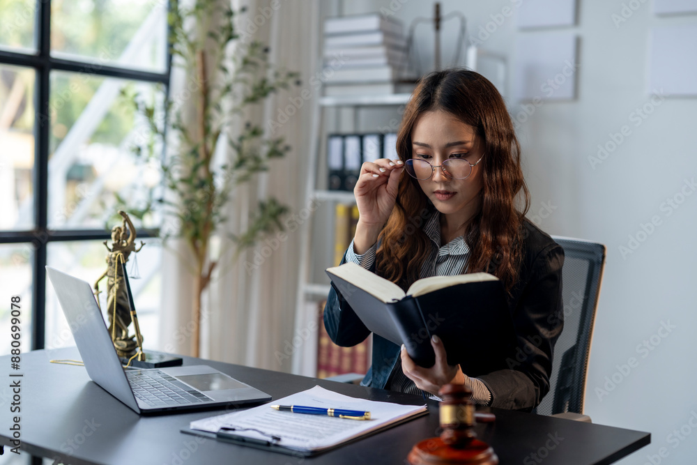 A woman is sitting at a desk with a laptop and a book A woman is sitting at a desk with a laptop and a book