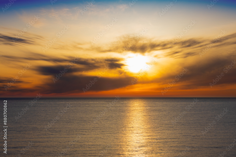 Dramatic golden sun among sky and grey clouds above the sea. Golden sunny path on the surface of ribbed water Dramatic golden sun among sky and grey clouds above the sea. Golden sunny path on the surface of ribbed water