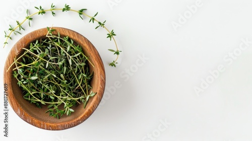 Thyme sprigs in a wooden bowl on a white backdrop with space for text