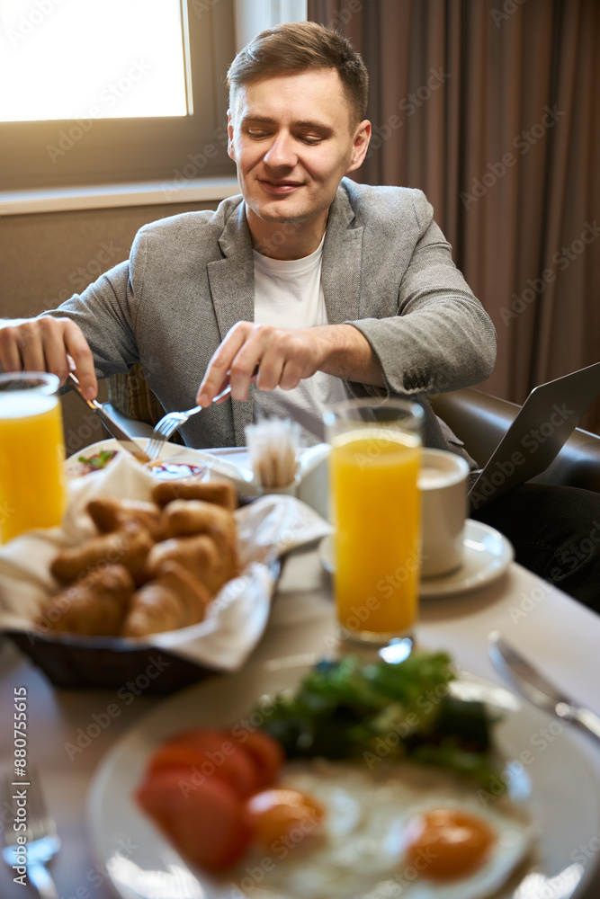 Pleased businessman having breakfast in his suite Pleased businessman having breakfast in his suite