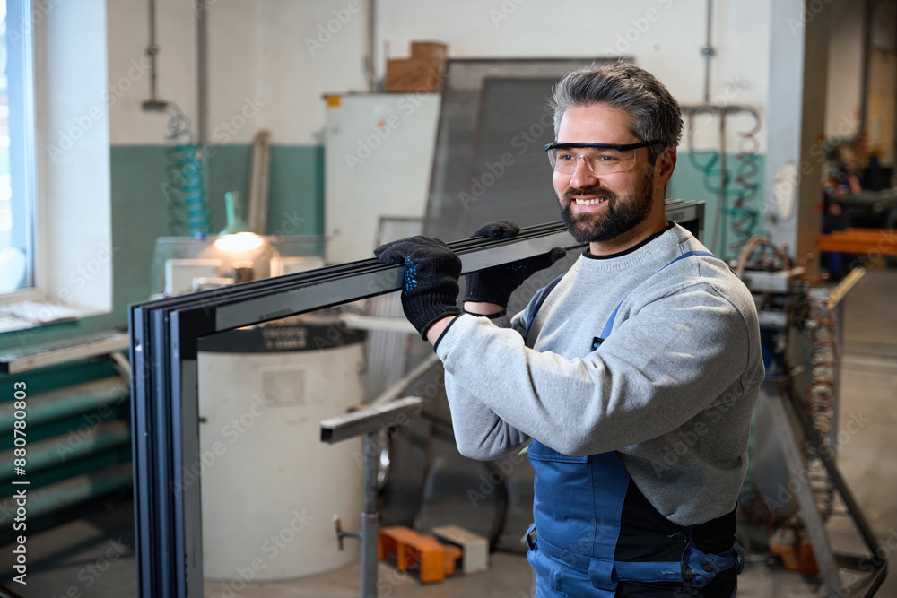 Specialist in work overalls carries window frame made of aluminum profile Specialist in work overalls carries window frame made of aluminum profile
