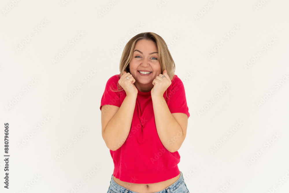 Headshot of pleased high spirit pretty female model, has warm pleasant smile, keeps hands under chin, wears red t-shirt, isolated over white background. Happiness concept Headshot of pleased high spirit pretty female model, has warm pleasant smile, keeps hands under chin, wears red t-shirt, isolated over white background. Happiness concept