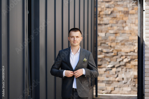 Obraz na płótnie A man in a suit is standing in front of a brick wall