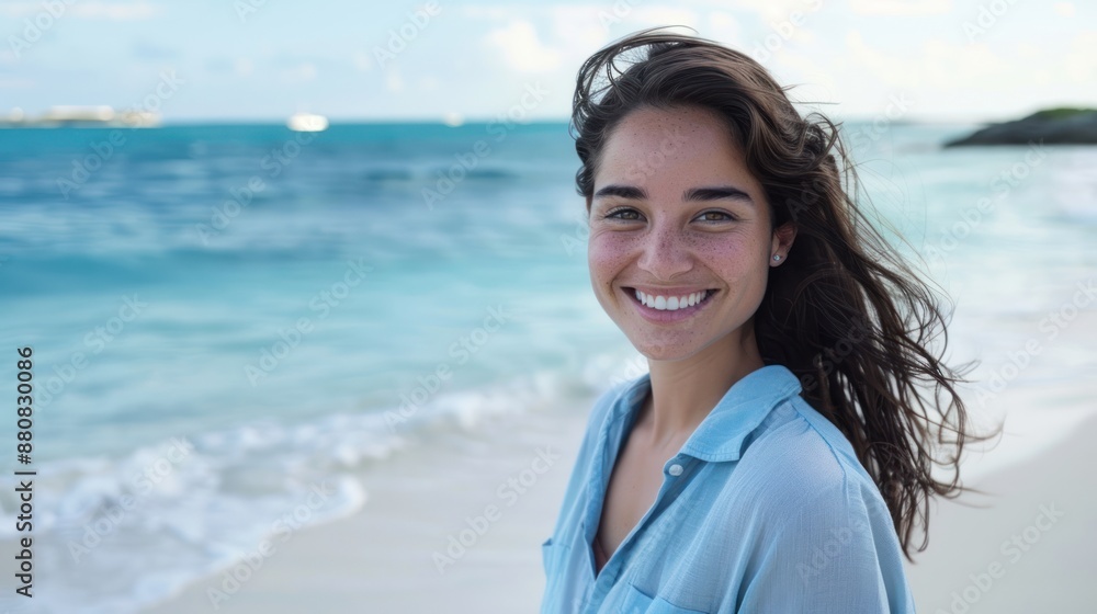 Portrait of a beautiful woman smiling at the camera on the beach, a young Latin Hispanic girl standing at the beach. Happy girl in a casual outfit with wind in her hair. enjoying vacation.