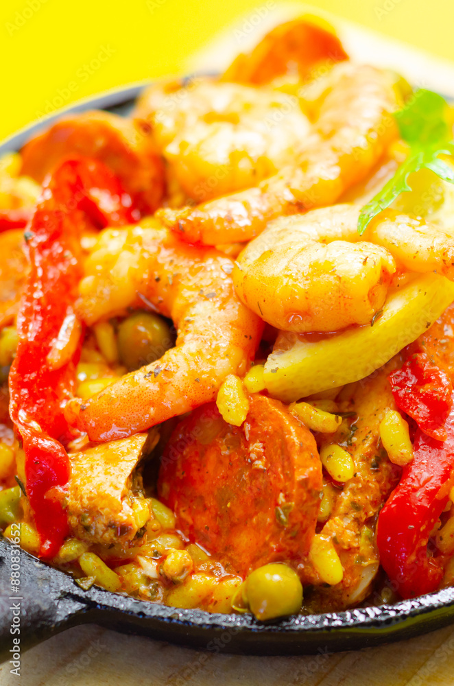 A black pan filled with a variety of food including shrimp, peppers, and corn