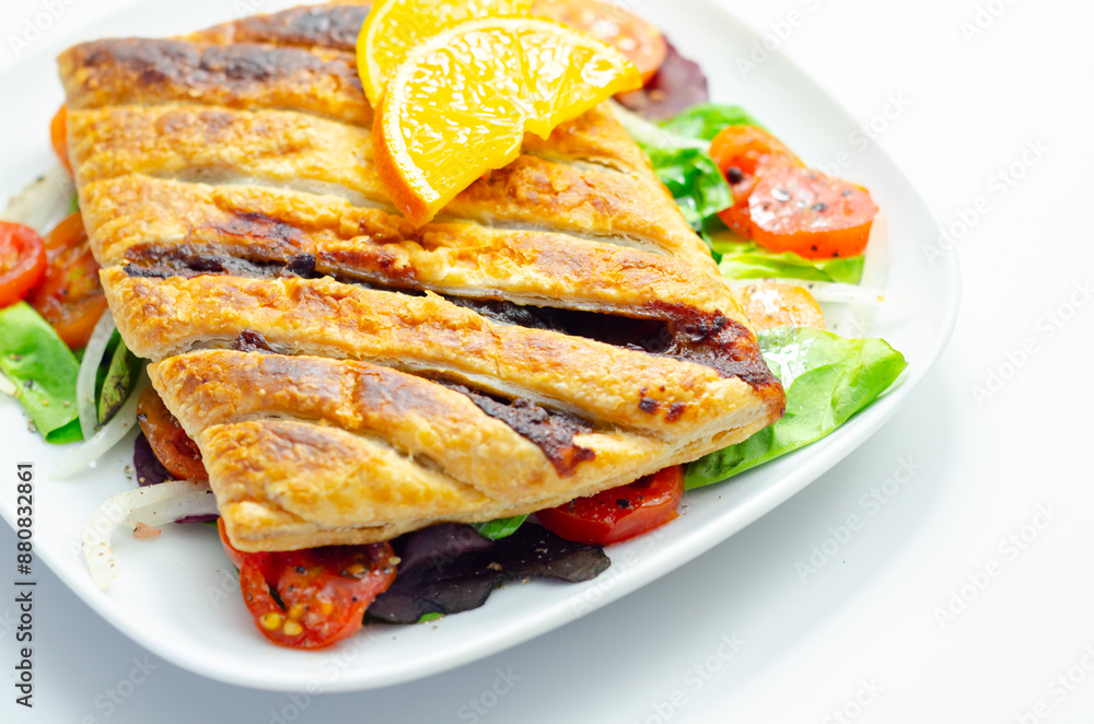 A plate of food with a pastry and a slice of orange on top A plate of food with a pastry and a slice of orange on top