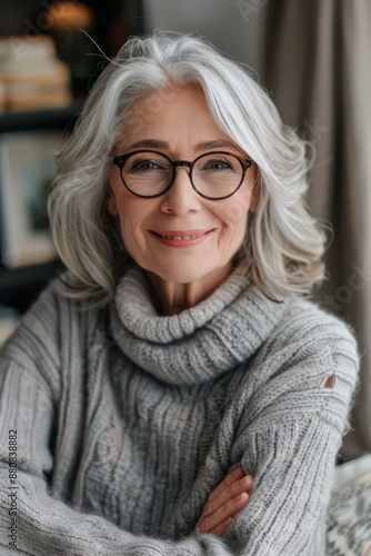 A woman with glasses and a gray sweater is smiling