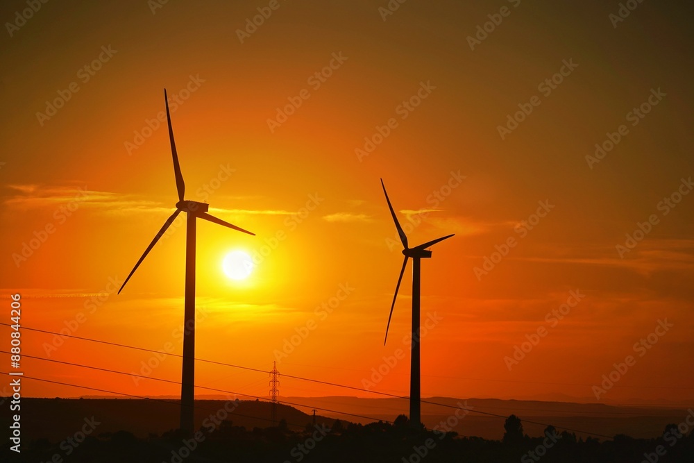 Siluetas de molinos de viento con el Sol al atardecer. Energías renovables Siluetas de molinos de viento con el Sol al atardecer. Energías renovables